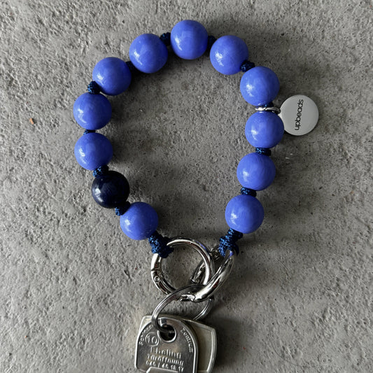 Violet-Blue wooden beaded upbeads keychain on a textured surface
