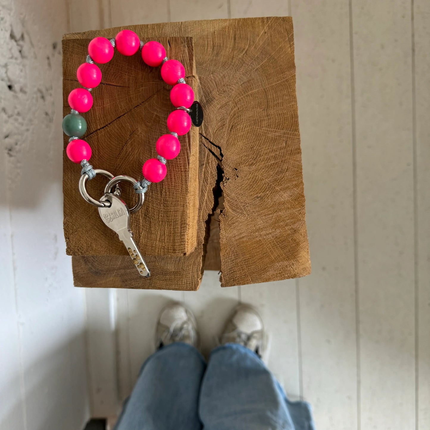 upbeads neon pink lady mini als schlüsselkette auf einen Holzbalken