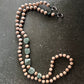 Beaded necklace with green stones on a dark surface. upbeads