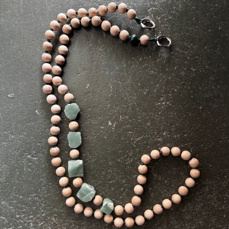 Beaded necklace with green stones on a dark surface. upbeads