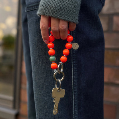 model holds upbeads mini foxy in neon orange wooden beads as a keychain