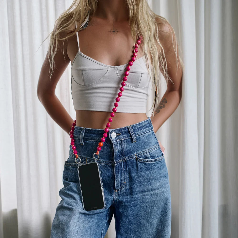upbeads berry crossbody worn on model with blue jeans and white cropped top the chain is attached to an upbeads iphone case