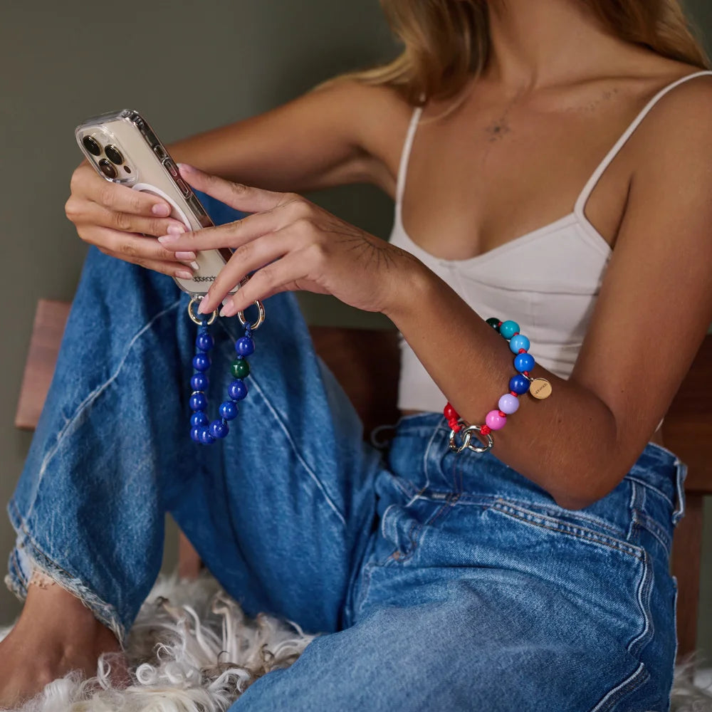 model is wearing a mini rainbow upbeads as a bracelet and an ocean model mini upbeads as a cellphone case