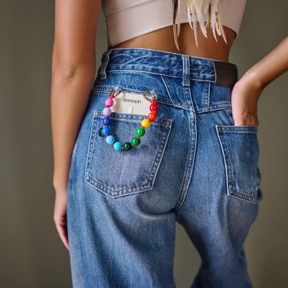 model back pocket carrying an upbeads mini rainbow attached to an upbeads phone case used as a phone chain
