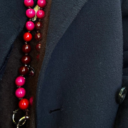 upbeads cellphone chain mixture of bordeaux, brigth pink and red FSC wooden beads worn as a necklace on dark brown cashmere sweater and dark blue jacket