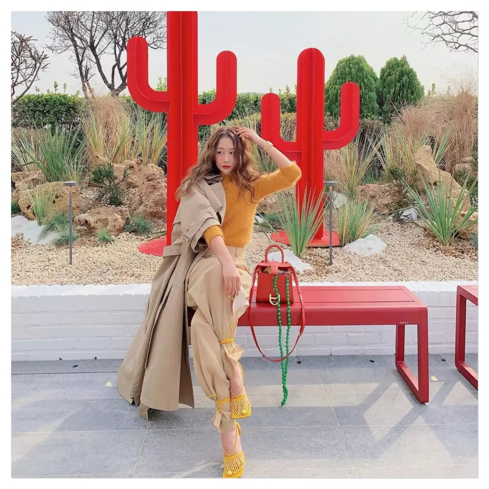 woman sitting on a bench in south korea park with her upbeads crossbody iceland hanging from her purse