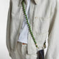 crossbody upbeads cellphone chain in olive green wooden beads worn by CLOSED model creme white jeans and creme white jeans jacket