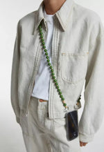 Load image into Gallery viewer, crossbody upbeads cellphone chain in olive green wooden beads worn by CLOSED model creme white jeans and creme white jeans jacket