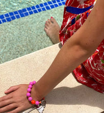 Laden Sie das Bild in den Galerie-Viewer, LOVE MINI PENDANT MINI UPBEADS person wearing love mini as a bracelet sitting by a pool summer accessory
