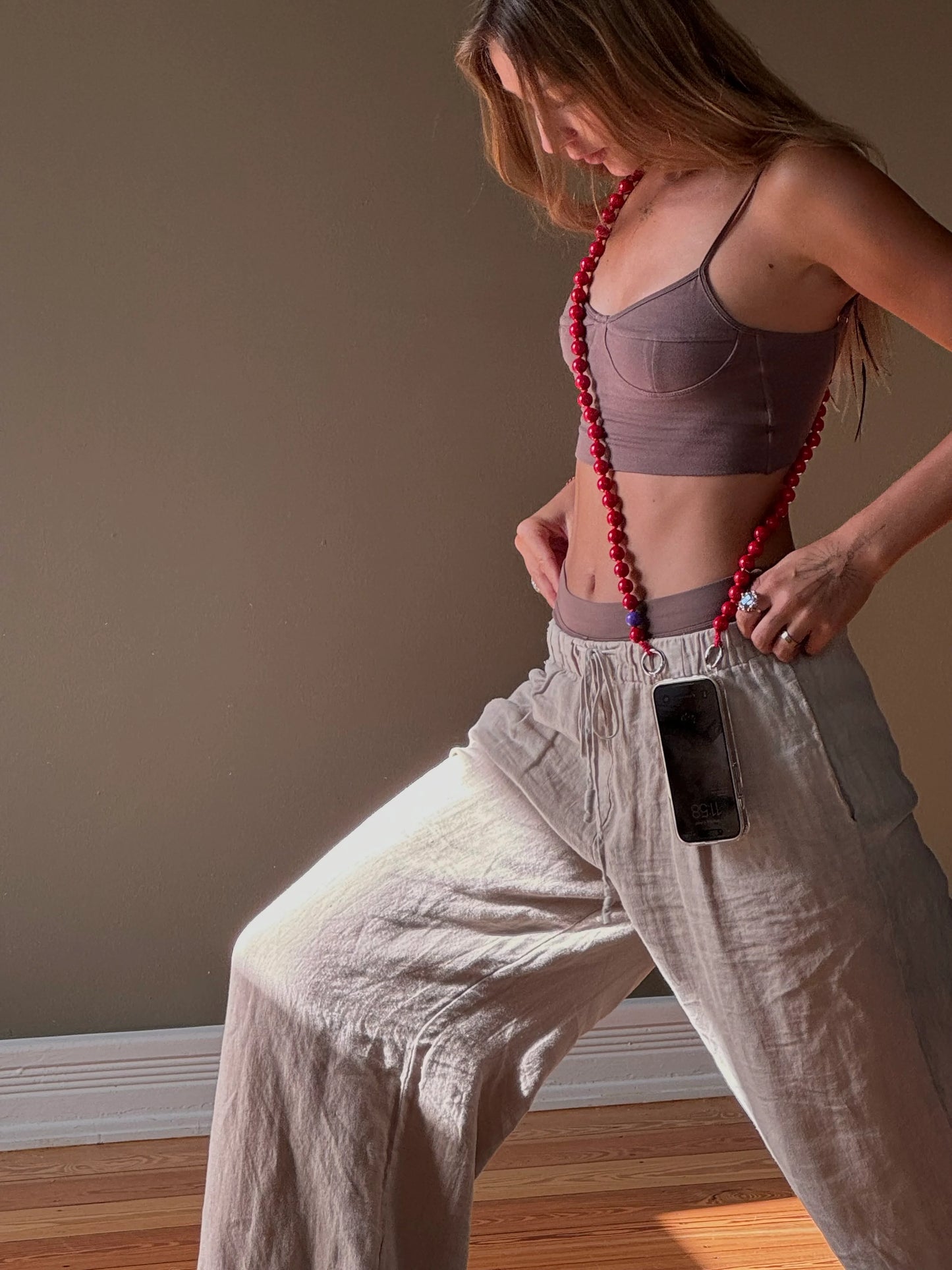 model Sina is wearing a crossbody simply red upbeads cellphone chain while practising yoga