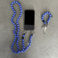 violet Blue wood beaded upbeads crossbody chain as a phone holder and keychain on a gray surface