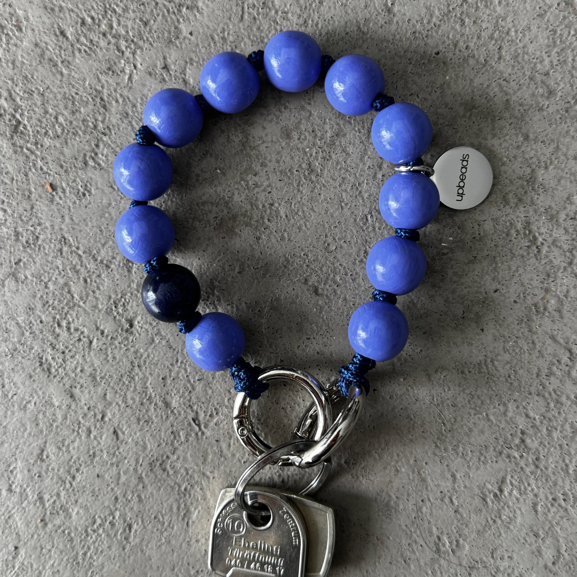 Violet-Blue wooden beaded upbeads keychain on a textured surface